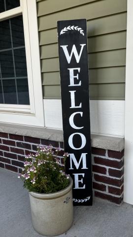 Black wooden "Welcome" porch sign.