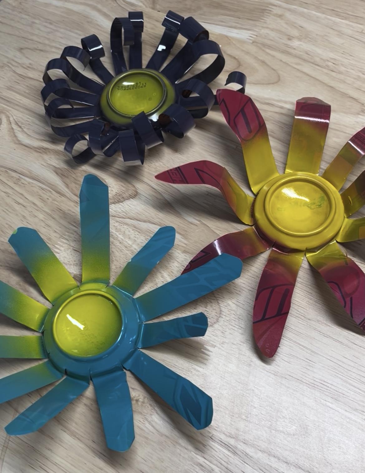 Image of 3 spray-painted flowers made from aluminum cans.