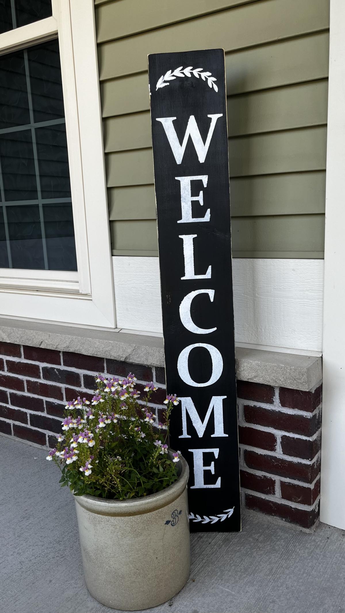 Black wooden "Welcome" porch sign.